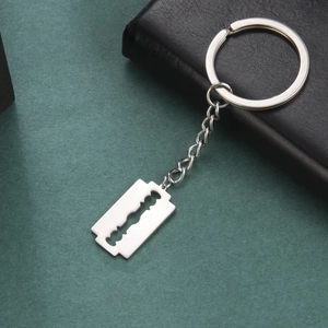 Silver razor blade pendant keychain in polished stainless steel on leather background