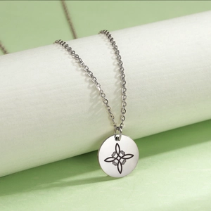 Minimalist stainless steel necklace with Celtic knot pendant on light green background