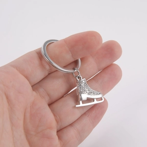Vue détaillée du porte-clés patin à glace en argent avec strass blancs tenu dans la main