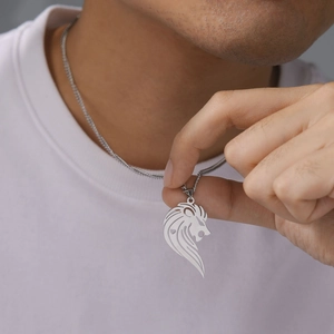 Nahaufnahme eines hohlen Löwenkopf-Anhängers an einer Edelstahlkette, getragen von einem Mann
