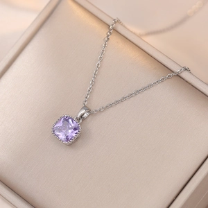 Détail macro d'un collier argenté avec pendentif en zircon violet carré dans son écrin