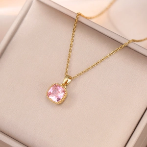 Détail d'un pendentif en zircon rose carré avec bordure perlée dorée sur une chaîne d'or