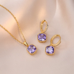 Détails d'un ensemble de collier et boucles d'oreilles dorés avec pierres de zircon mauves
