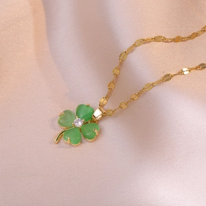 Elegant gold titanium necklace with green clover pendant and zircon on satin fabric