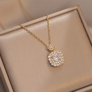 Macro-opname van een gouden ketting met een vierkante dubbele halo-hanger en kristallen
