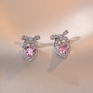 Primer plano de pendientes de corazón con circón rosa y detalle de lazo brillante