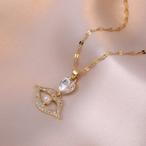 Collier doré avec pendentif cœur et œil, perle et cristaux sur satin champagne