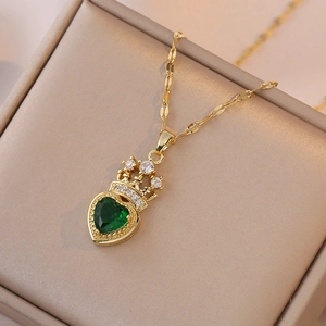 Collier élégant doré avec pendentif cœur émeraude et détail couronne sur boîte à bijoux