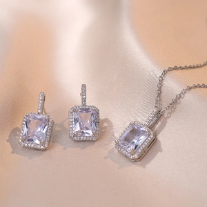 Parure de bijoux argentés avec zircons rectangulaires taille émeraude sur satin champagne