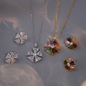 Détail de l'ensemble collier et boucles d'oreilles fleur en zircon sur tissu texturé