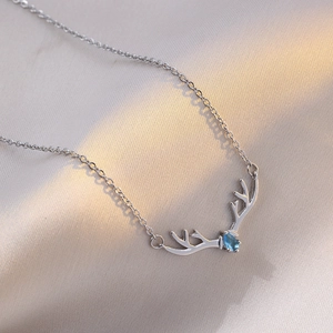 Reindeer antler necklace with blue marquise stone on soft silk fabric background