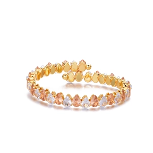 Makro-Detail eines goldenen Spiralarmbands mit abwechselnd champagnerfarbenen Zirkonia