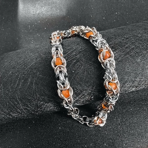 Byzantine chain bracelet with orange beads and lobster clasp on black display stand