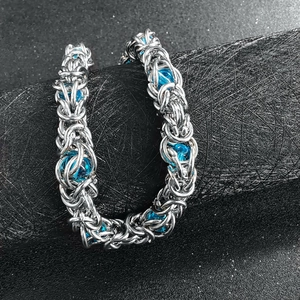 Detail of silver chain bracelet with blue beads on a black textured display