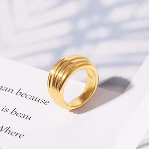 Makro-Detail eines breiten goldenen Edelstahlrings mit horizontaler Wellenstruktur