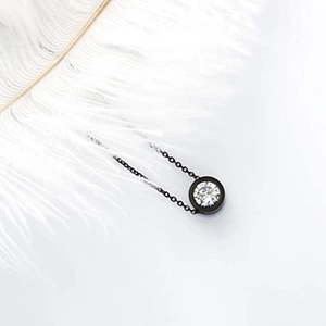 Vue détaillée d'un pendentif solitaire rond avec cadre noir et pierre en cristal clair