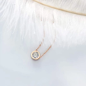 Gros plan d'un collier en or rose avec un pendentif diamant sur une plume blanche douce