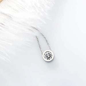 Détail d'un collier pendentif solitaire minimaliste avec une fine chaîne en argent sur blanc