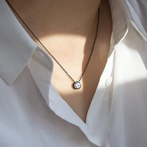 Détail macro d'un pendentif solitaire minimaliste sur une fine chaîne noire élégante