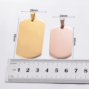 Primer plano de placas de perro de acero inoxidable en oro y oro rosa con regla de medida