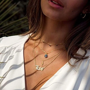 Détail d'un collier doré multicouche avec pendentif Leo et breloques en éclair chic