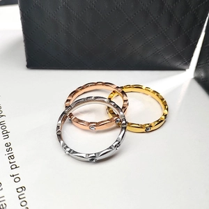 Detalle de tres anillos finos ondulados en plata, oro rosa y oro con cristales