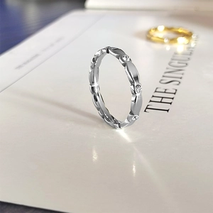 Detalle de anillos ondulados en oro rosa y plata con cristales blancos y estilo minimalista
