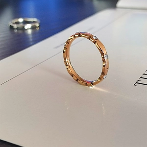 Detalle macro de anillo ondulado en oro rosa con circonitas incrustadas y facetas pulidas