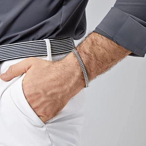 Men's silver stainless steel Cuban link bracelet styled on wrist with smart casual attire