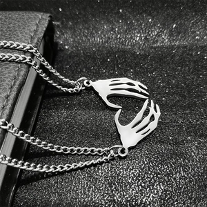 Macro shot of punk gothic skeleton hands forming a heart pendant on stainless steel chain