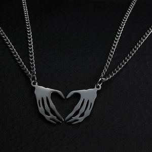 Close-up of gothic stainless steel necklace with skeleton hands forming a heart pendant