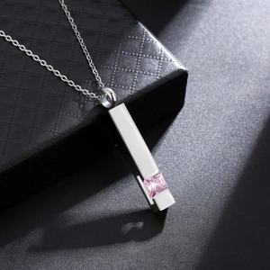 Close-up of geometric steel pendant with pink gemstone on a premium jewelry box
