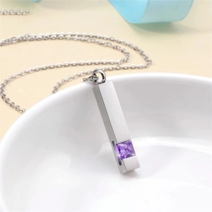 Geometric stainless steel urn necklace with purple gemstone for ashes on white bowl