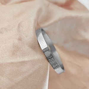Macro view of Chinese heart sutra scripture and lotus pattern on silver stainless steel cuff