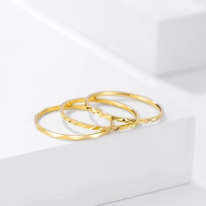 Detailed view of three minimalist gold-tone stackable rings with diamond-cut patterns
