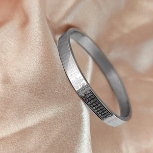 Macro shot of silver stainless steel cuff bracelet with engraved Heart Sutra text