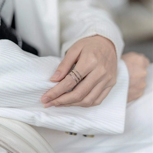 Detail view of three minimalist silver titanium steel rings with textured patterns on finger