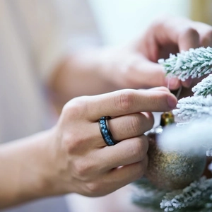 Men's black titanium steel rotatable ring with blue carbon fiber inlay against holiday background