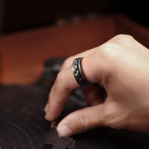 Close-up of matte black gear ring for men on hand with a vintage turntable background
