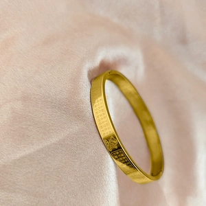 Detail view of gold stainless steel bangle with engraved Buddhist Heart Sutra and Buddha