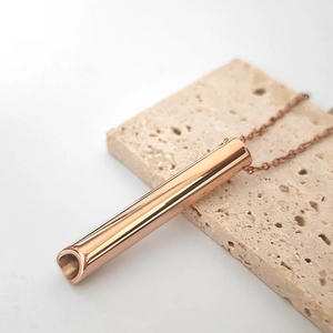 Detalle del colgante silbato de meditación oro rosa con superficie pulida en piedra