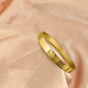 Detailed macro of gold stainless steel bangle with engraved Buddhist Heart Sutra scriptures