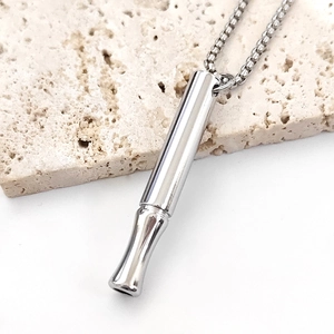 Primer plano de colgante cilíndrico de acero inoxidable para meditación en base piedra