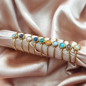 Dettaglio di anelli con pietre rotonde multicolore in montatura minimalista oro 18K