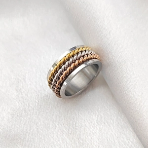 Makro-Detail eines breiten dreifarbigen geflochtenen Spinner-Rings aus Gold, Silber und Roségold