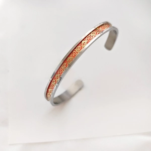 Close-up of titanium steel cuff bangle with red base and golden dragon pattern engraving