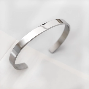 Vista macro di un bracciale aperto minimalista argento con superficie liscia e piatta