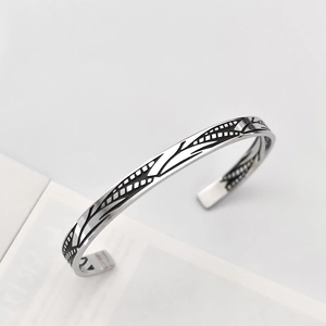 Dettaglio del bracciale rigido vintage in argento con motivi di foglie nere e design aperto