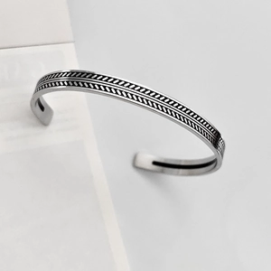 Dettaglio del bracciale rigido argento con motivi geometrici neri incisi in parallelo