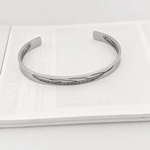 Dettaglio di un bracciale rigido vintage in argento con incisione di foglie di piume